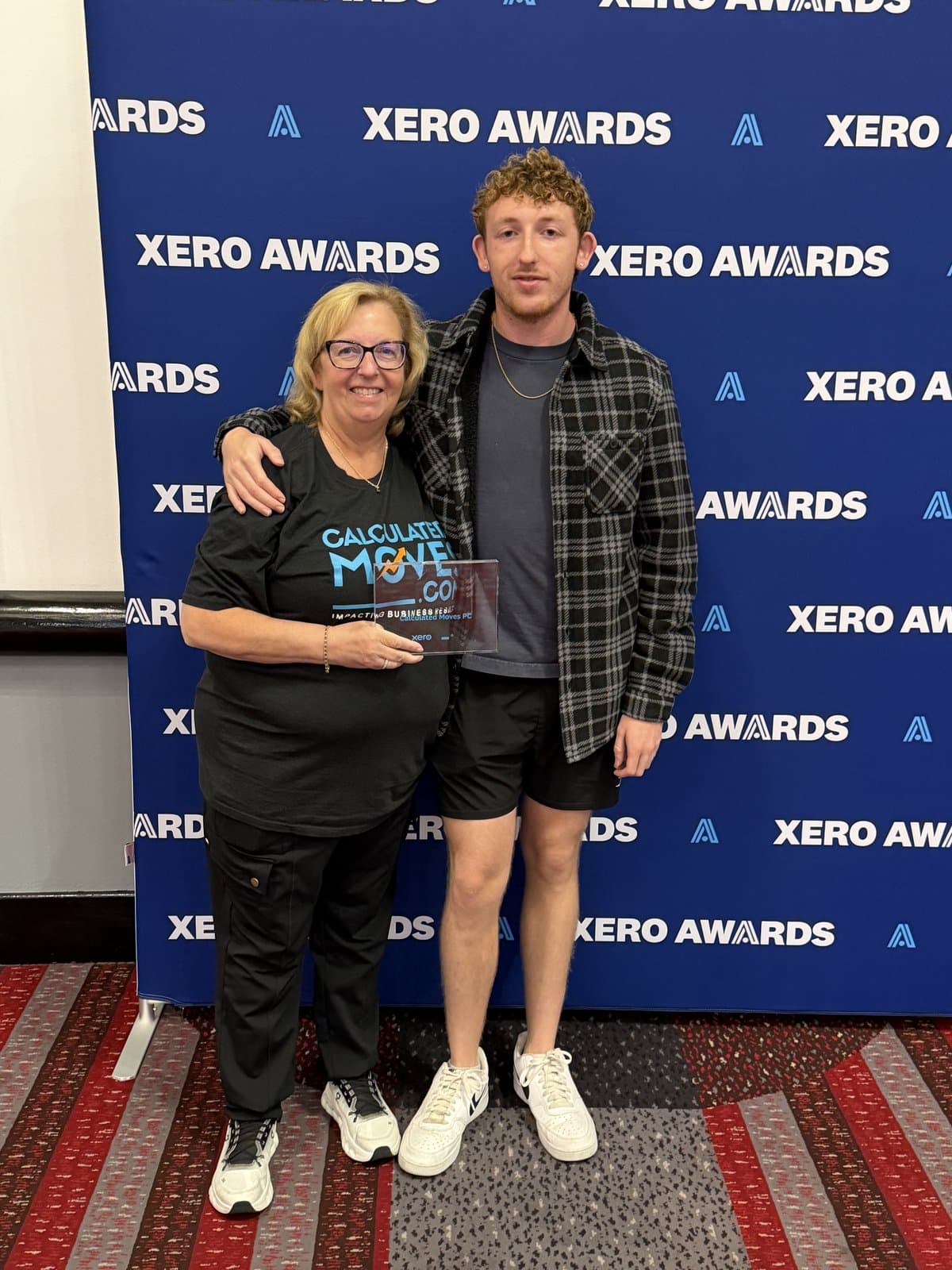 Donna and Zack Bordeaux holding the Small Firm of the Year award in front of the Xero Awards backdrop
